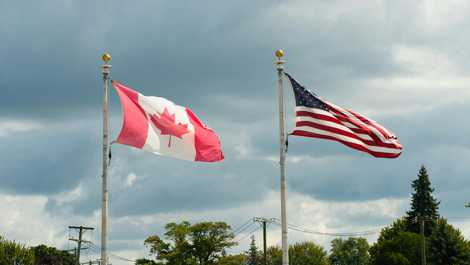 Image of Canadian and US Flags on Poles blowing in the breeze